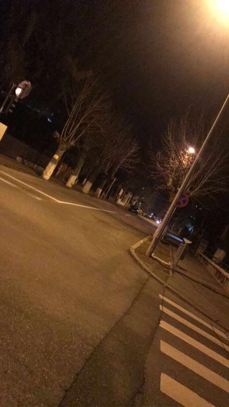 an empty street at night with no cars or people on the road and trees in the background