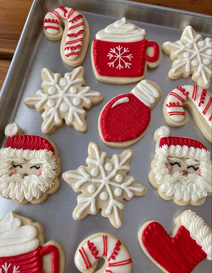 decorated cookies in the shape of santa claus and snowflakes on a baking sheet