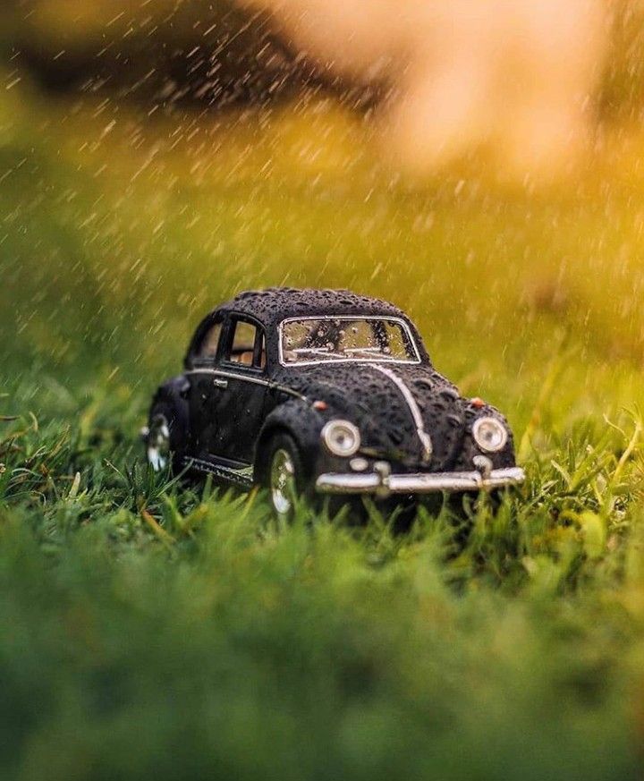 a toy car sitting in the grass with rain coming down on it's roof