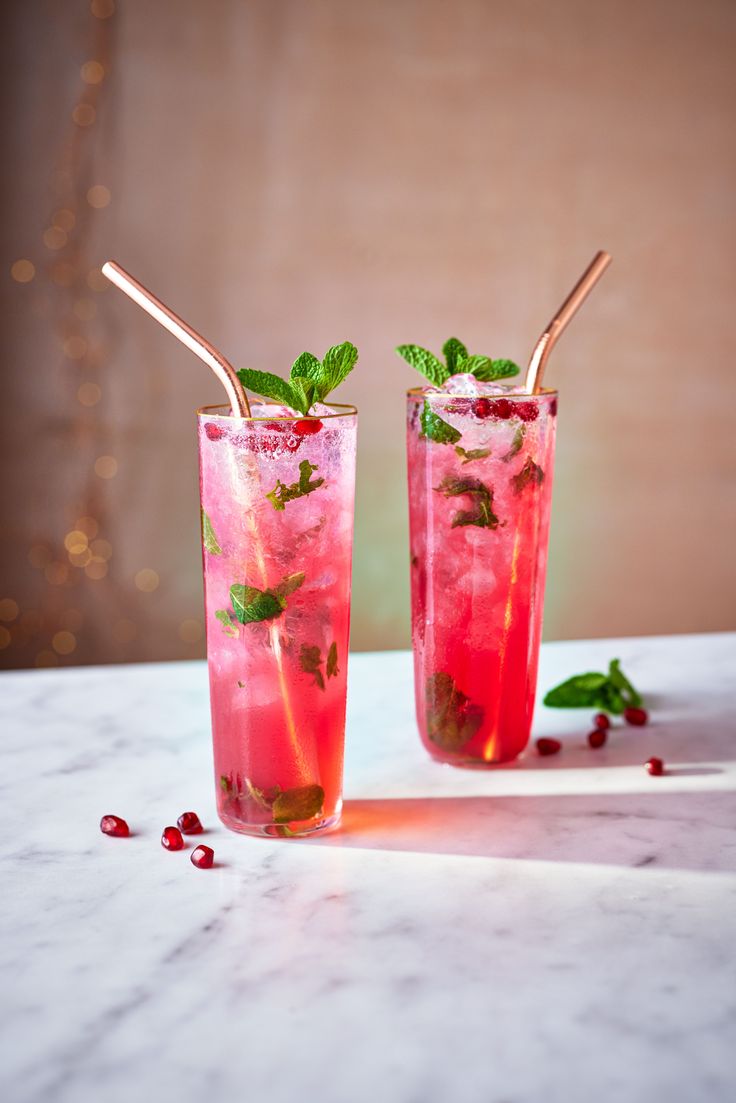 two glasses filled with ice and garnish on top of a white marble table