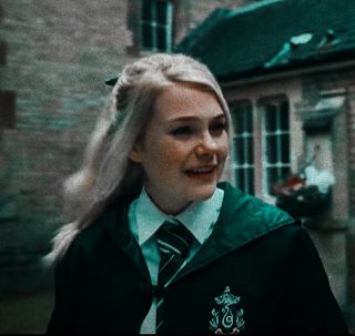 a woman with long blonde hair wearing a harry potter uniform and smiling at the camera