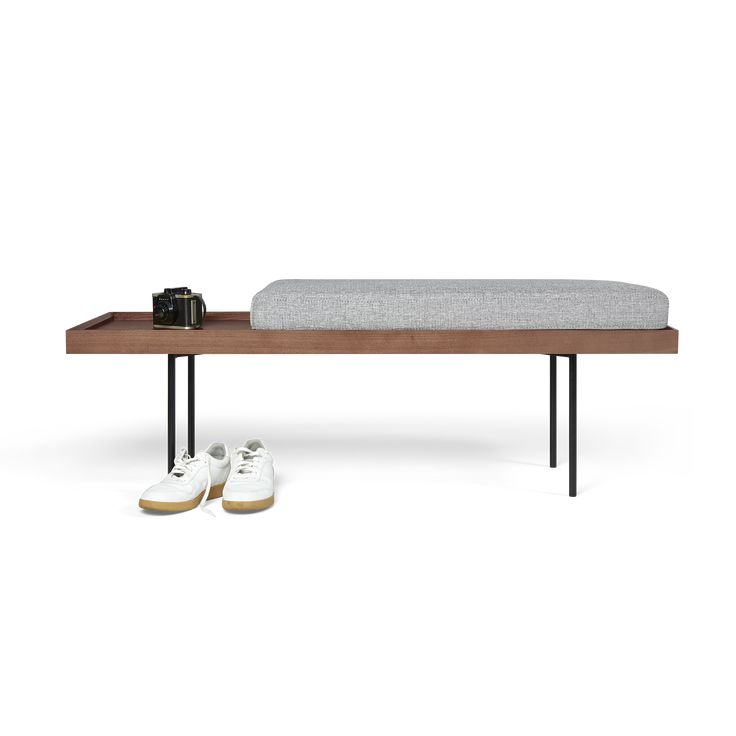 a wooden bench with two shoes on it and a phone sitting next to the bench