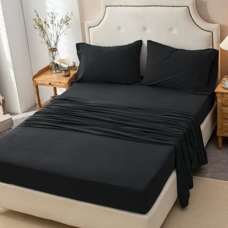 a bed with black sheets and pillows in a room