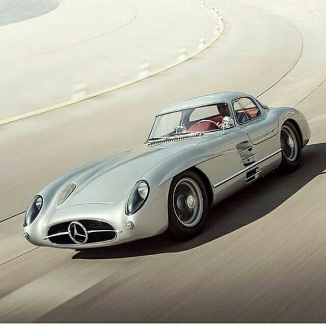 an old mercedes sports car driving on a track with the driver in the front seat