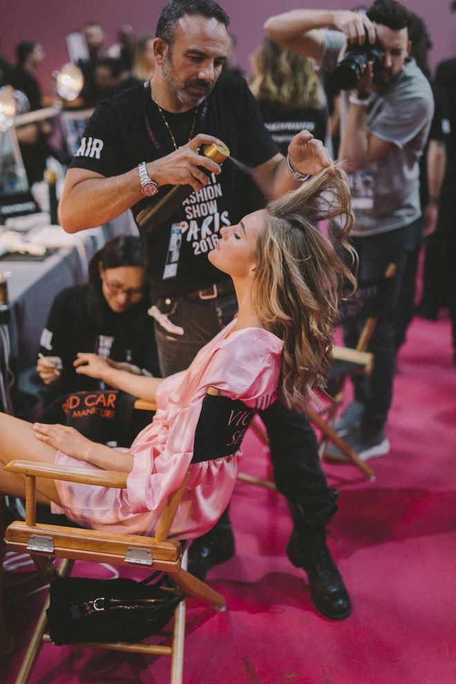 a woman getting her hair cut by a man in a black shirt and pink pants