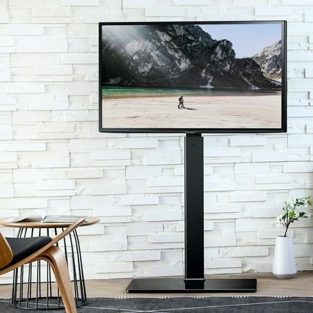 a flat screen tv sitting on top of a wooden stand next to a white brick wall