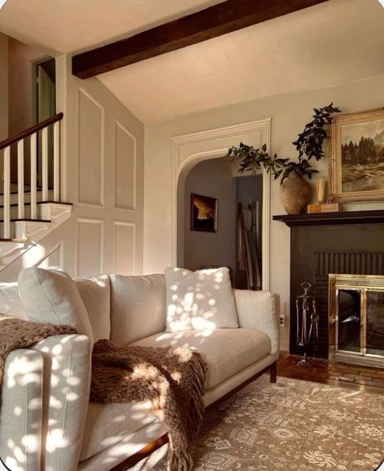 a living room filled with furniture and a fire place next to a staircase leading up to a second story