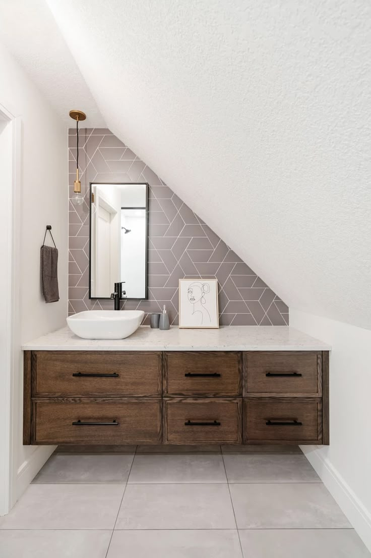 a bathroom with a sink, mirror and wooden cabinet under the slanted roofing