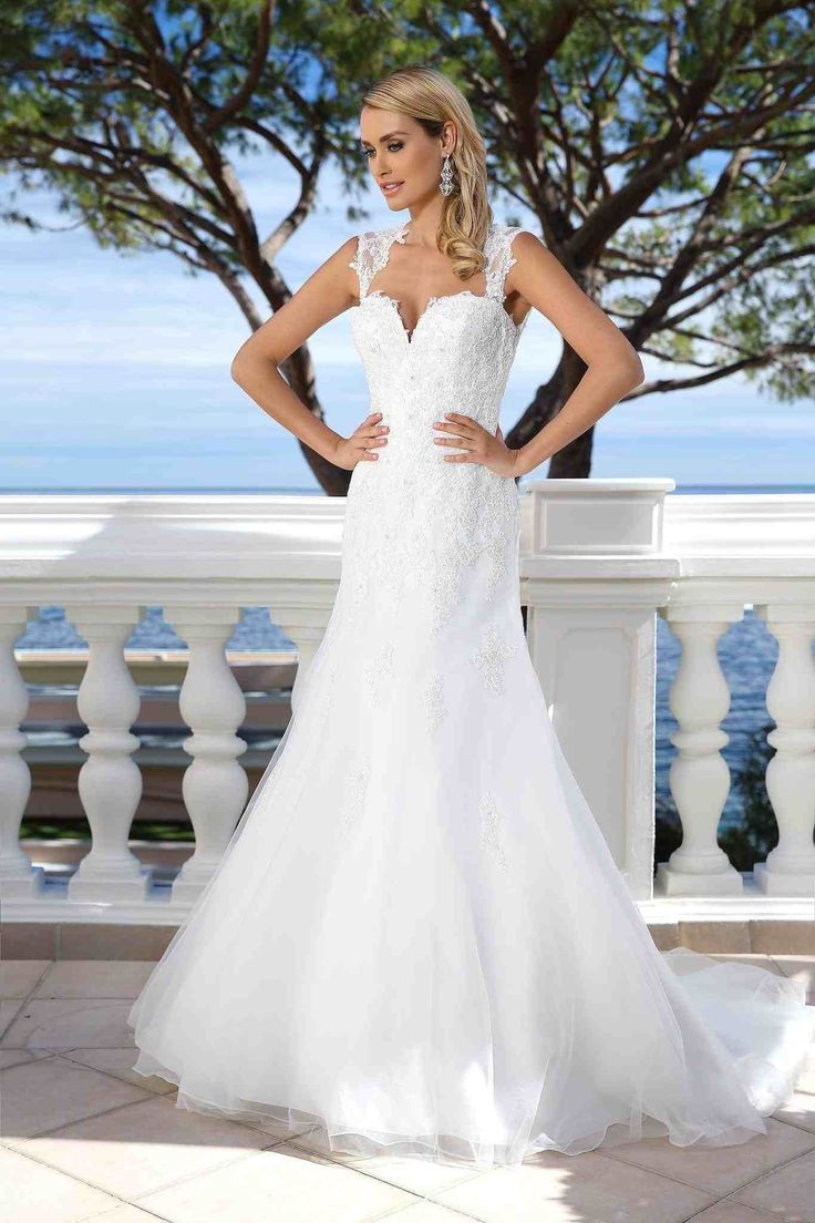 a woman in a wedding dress standing on a balcony with her hands on her hips