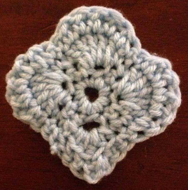 a crocheted flower sitting on top of a wooden table