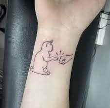 a person with a small tattoo on their arm holding a teddy bear in the air