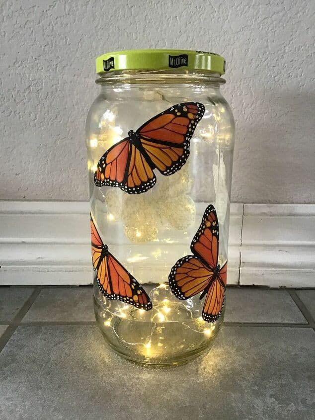 a glass jar with some lights in it and two orange butterflies on the top one