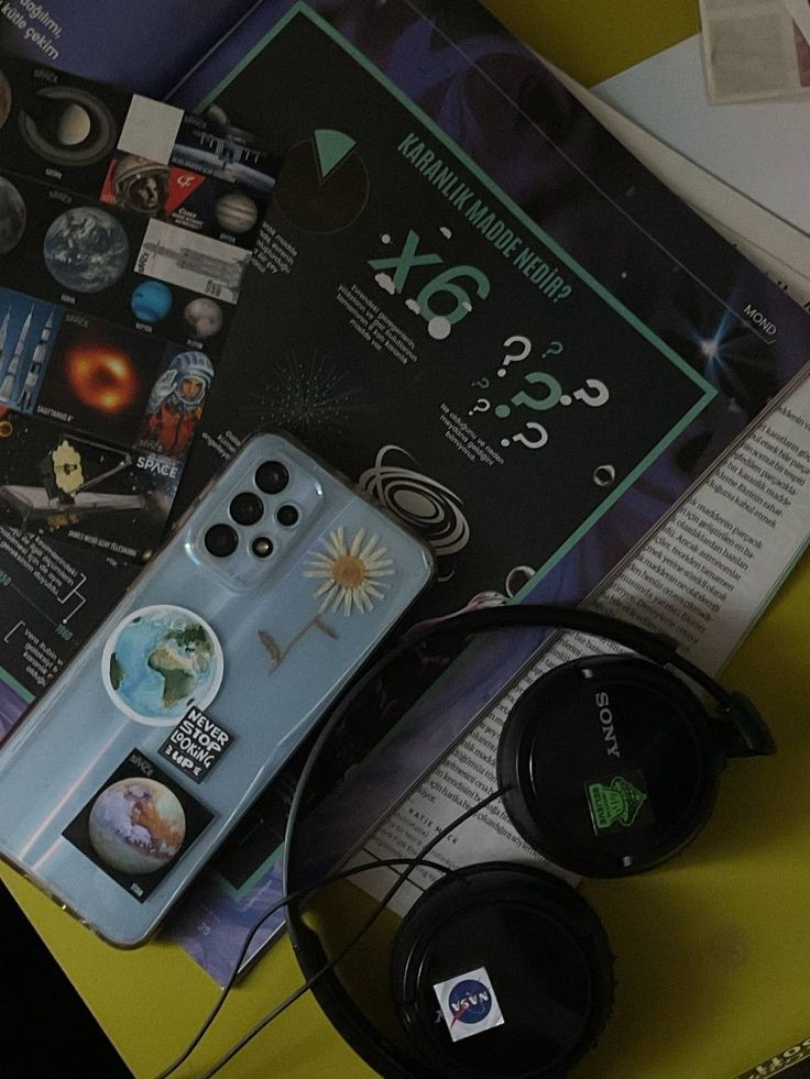 there is a remote control and headphones on the table next to some books that are open