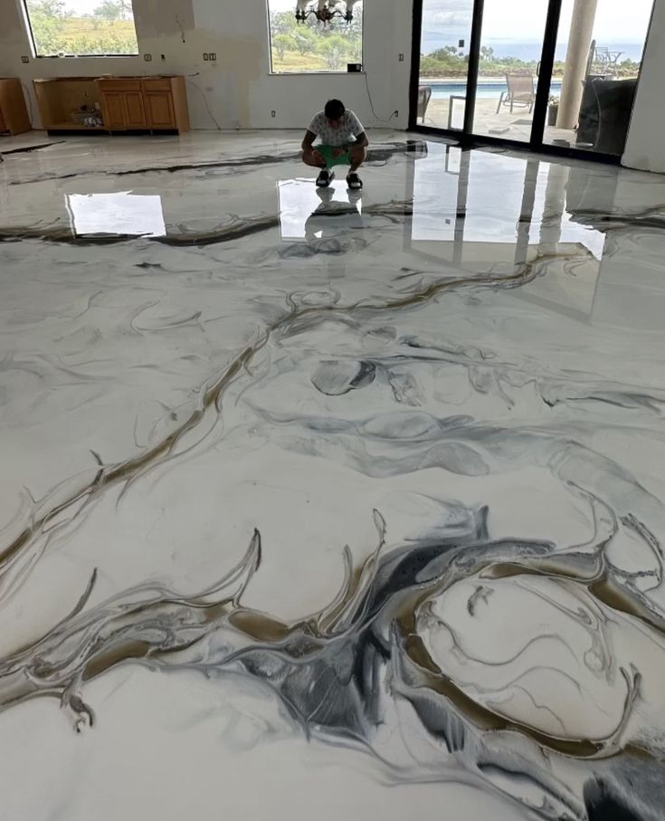 a man sitting on top of a white floor in a room with large glass doors