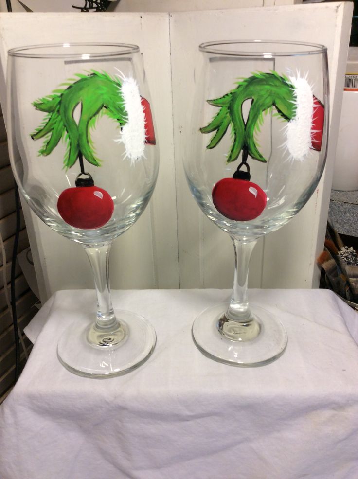 two wine glasses with painted designs on them are sitting on a white tablecloth covered surface