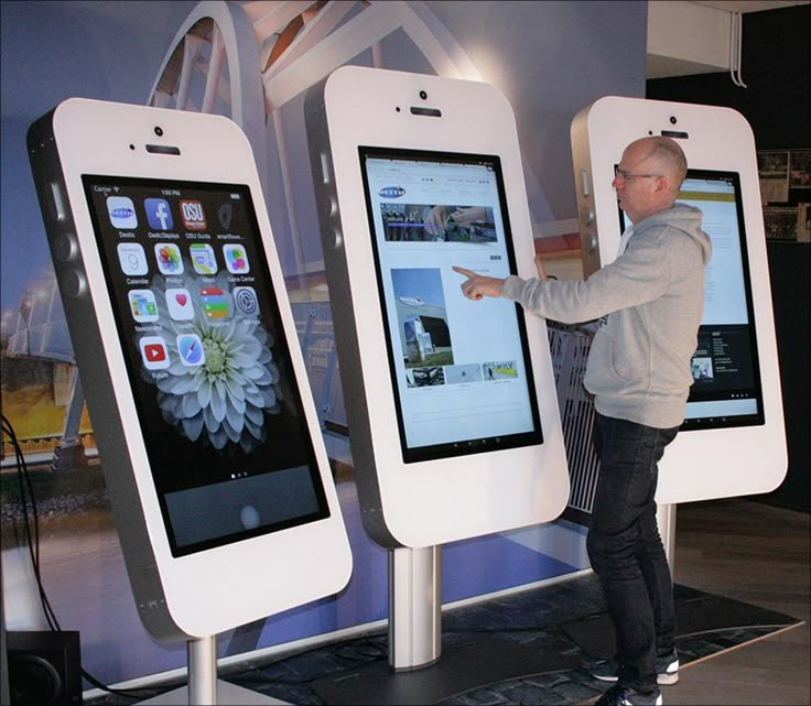 a man standing next to two large cell phones