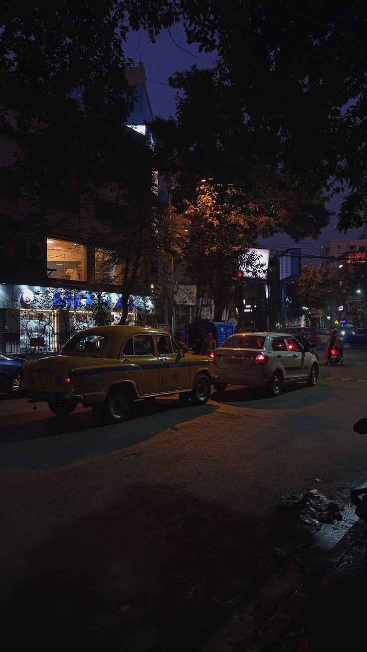 cars are parked on the side of the road at night