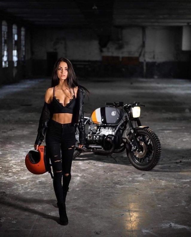 a woman walking in an empty garage with a motorcycle