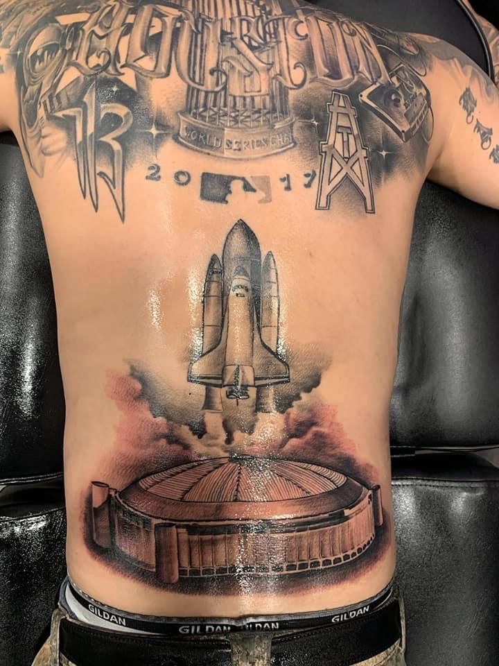 a man with a tattoo on his back has a space shuttle in the middle of it