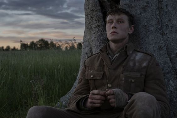 a man sitting next to a tree in the grass