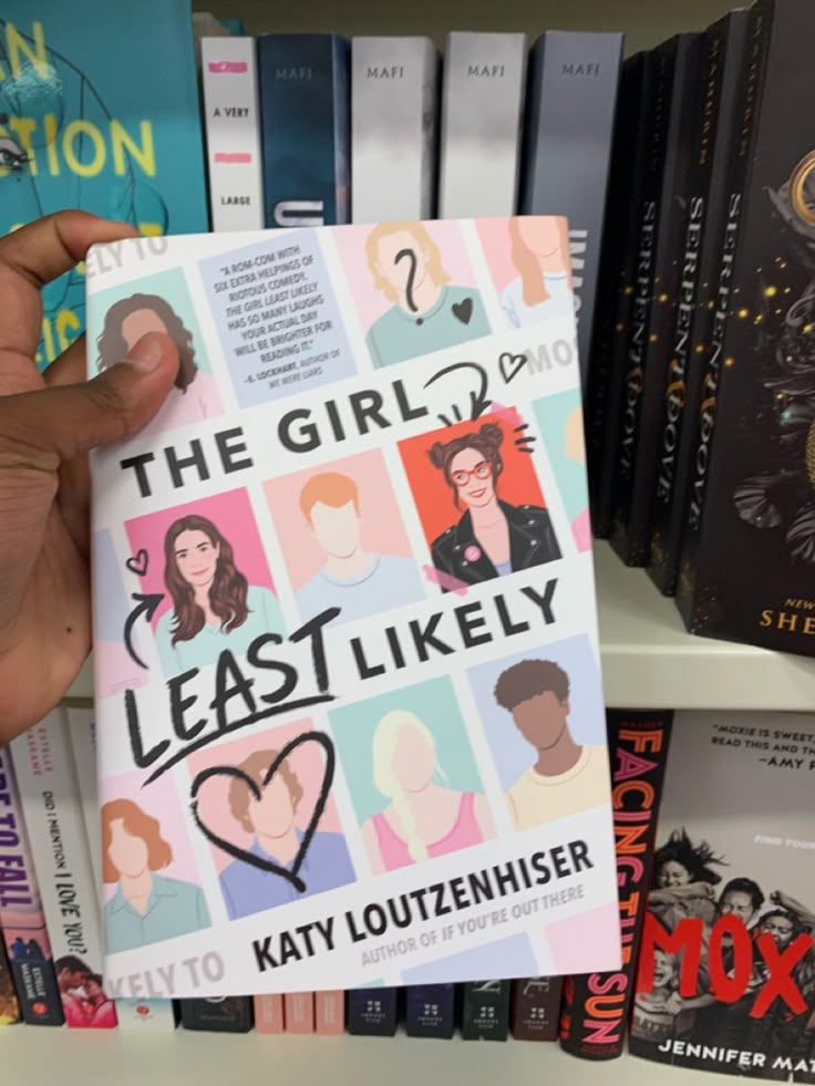 a person holding up a book in front of bookshelves with the title, the girl least likely