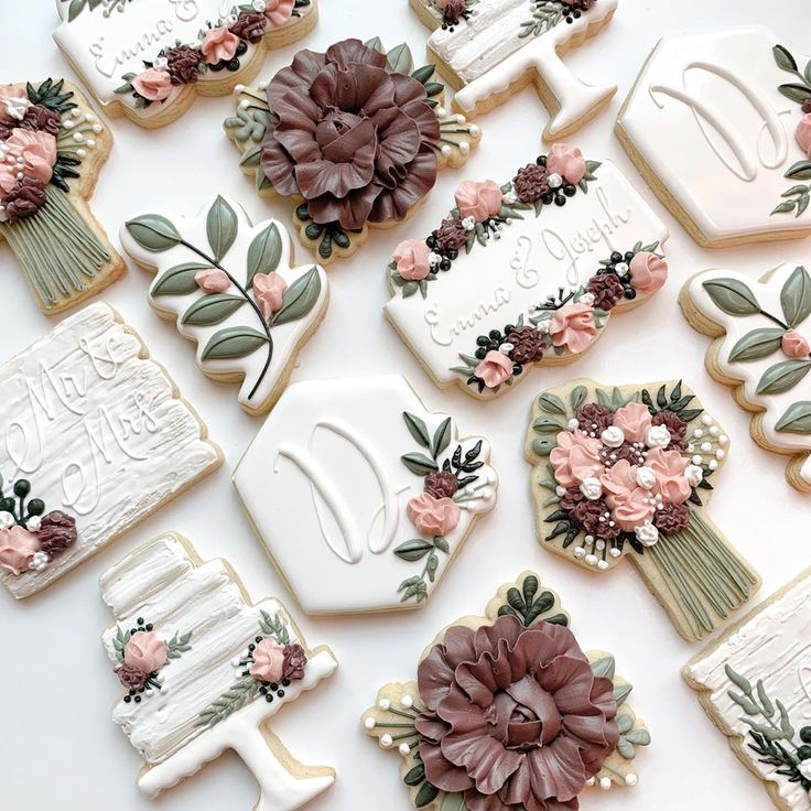 many decorated cookies with flowers and leaves on them are arranged in the shape of letters