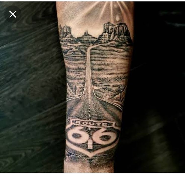 a man with a tattoo on his arm that has a road going through the mountains