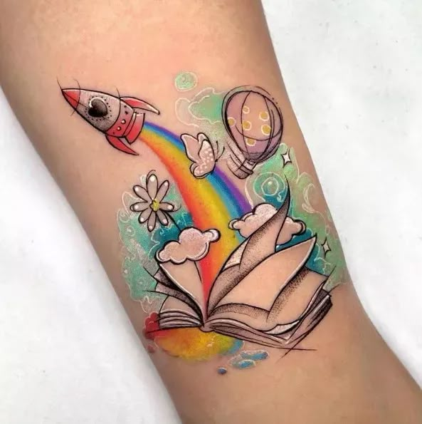 a colorful tattoo with an open book and rainbow