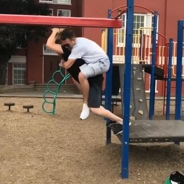 a man is jumping in the air on a playground equipment with his hands behind his head