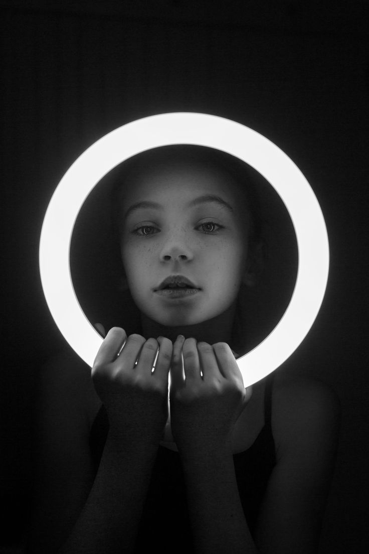 a woman with her hands on her face in front of a circular light