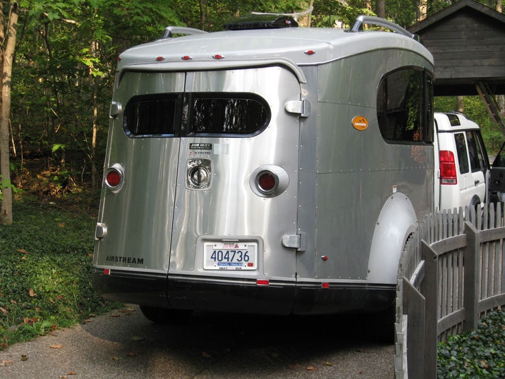 a silver trailer parked next to a wooden fence