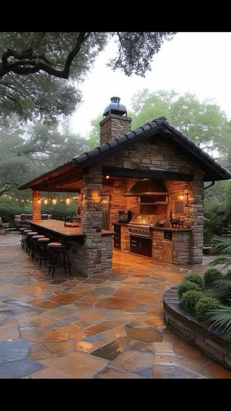 an outdoor kitchen is lit up at night with lights on the roof and grilling area