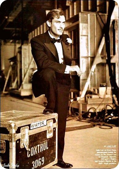 a man in a tuxedo standing next to a suitcase