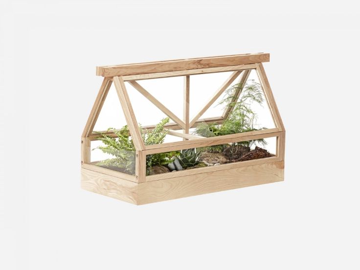 a small wooden greenhouse with plants inside