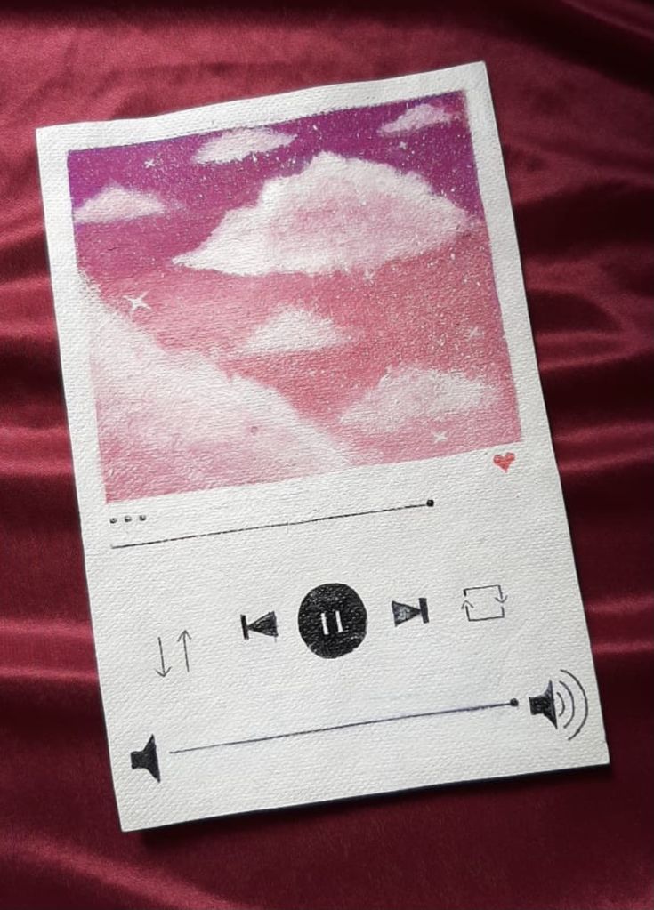 an mp3 player is laying on a red sheet with pink and white clouds in the background