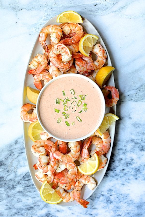 a plate filled with shrimp and lemons next to a dipping sauce