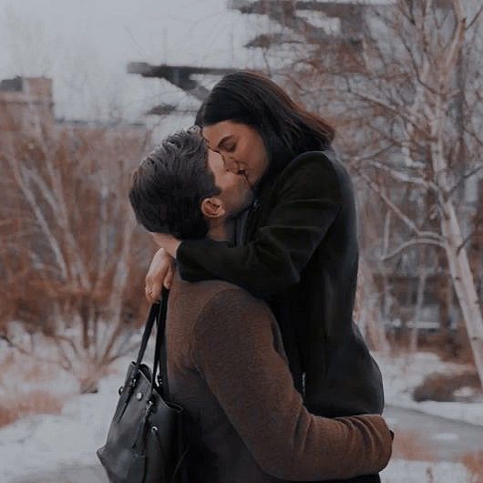 a man and woman kissing in the snow