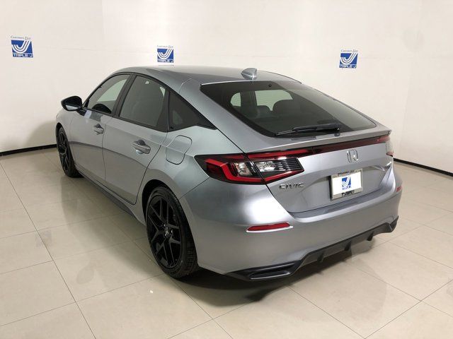 the rear end of a silver car parked in a room with white walls and tile flooring