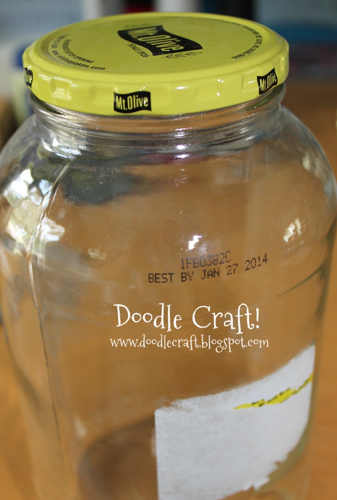 a glass jar filled with liquid sitting on top of a wooden table next to a yellow lid