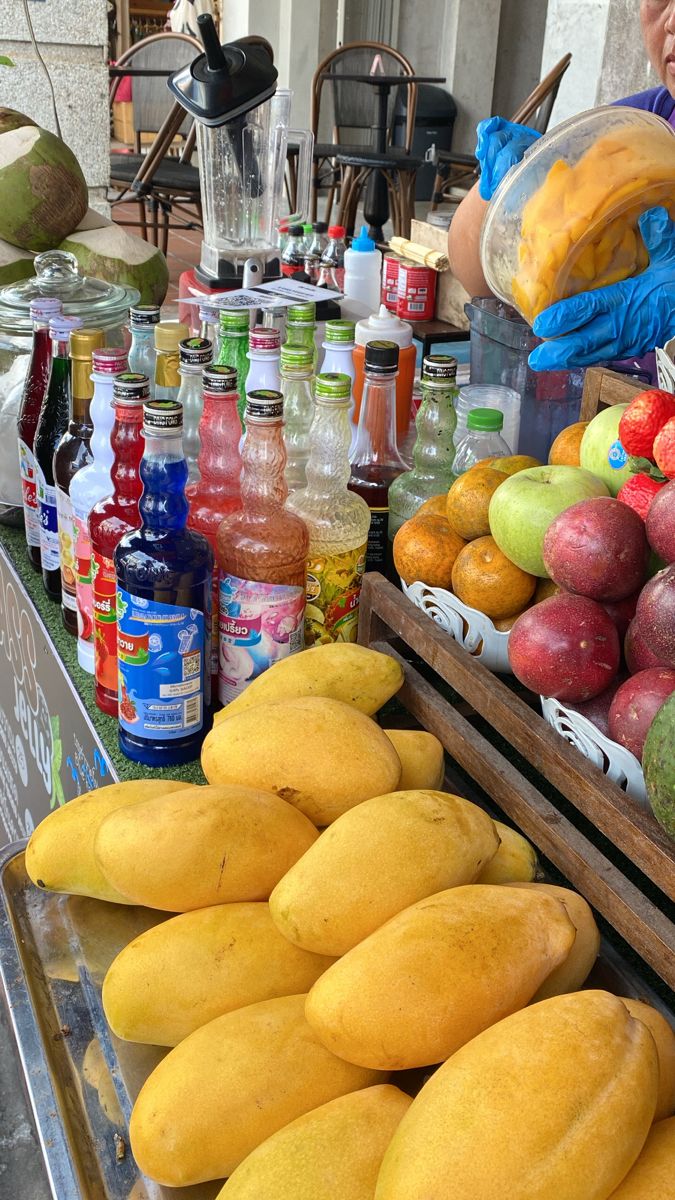 there are many different types of fruit on display at this outdoor market, including mangoes, apples, and watermelon