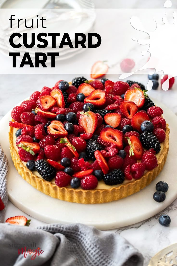 a fruit custard tart on a plate with berries and blueberries in the middle