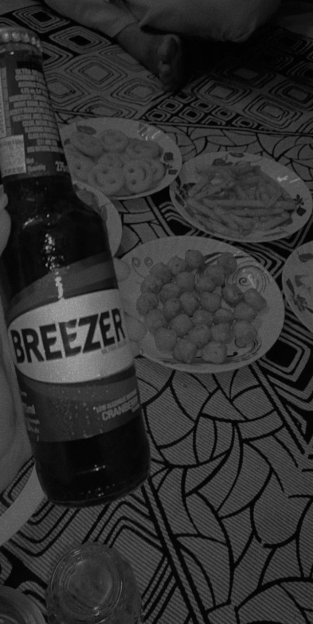 a bottle of beer sitting on top of a table next to plates of food and drinks