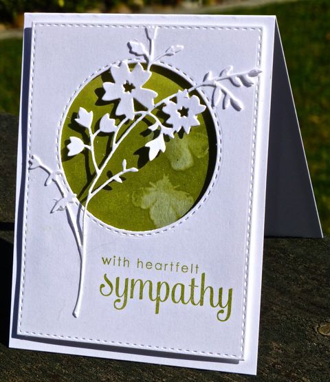 a card with white flowers on it and the words sympathy written in green, surrounded by grass