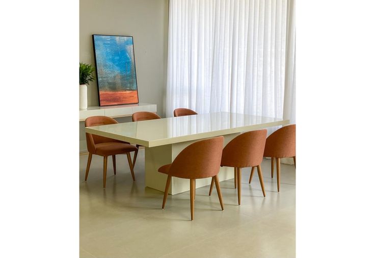 a dining room table with orange chairs and a large painting on the wall behind it