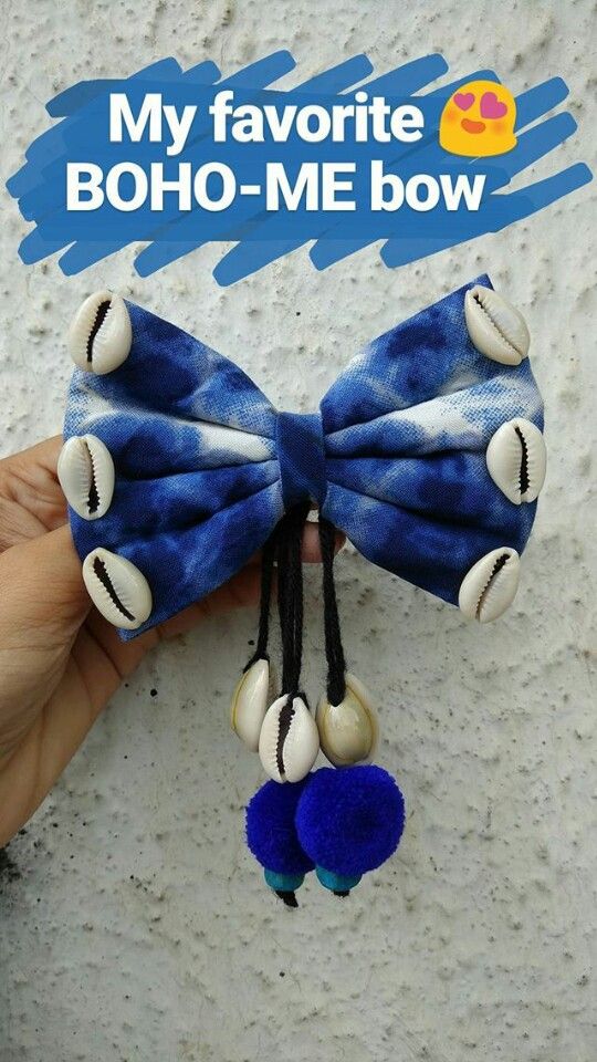 a hand holding a blue and white bow with shells on it