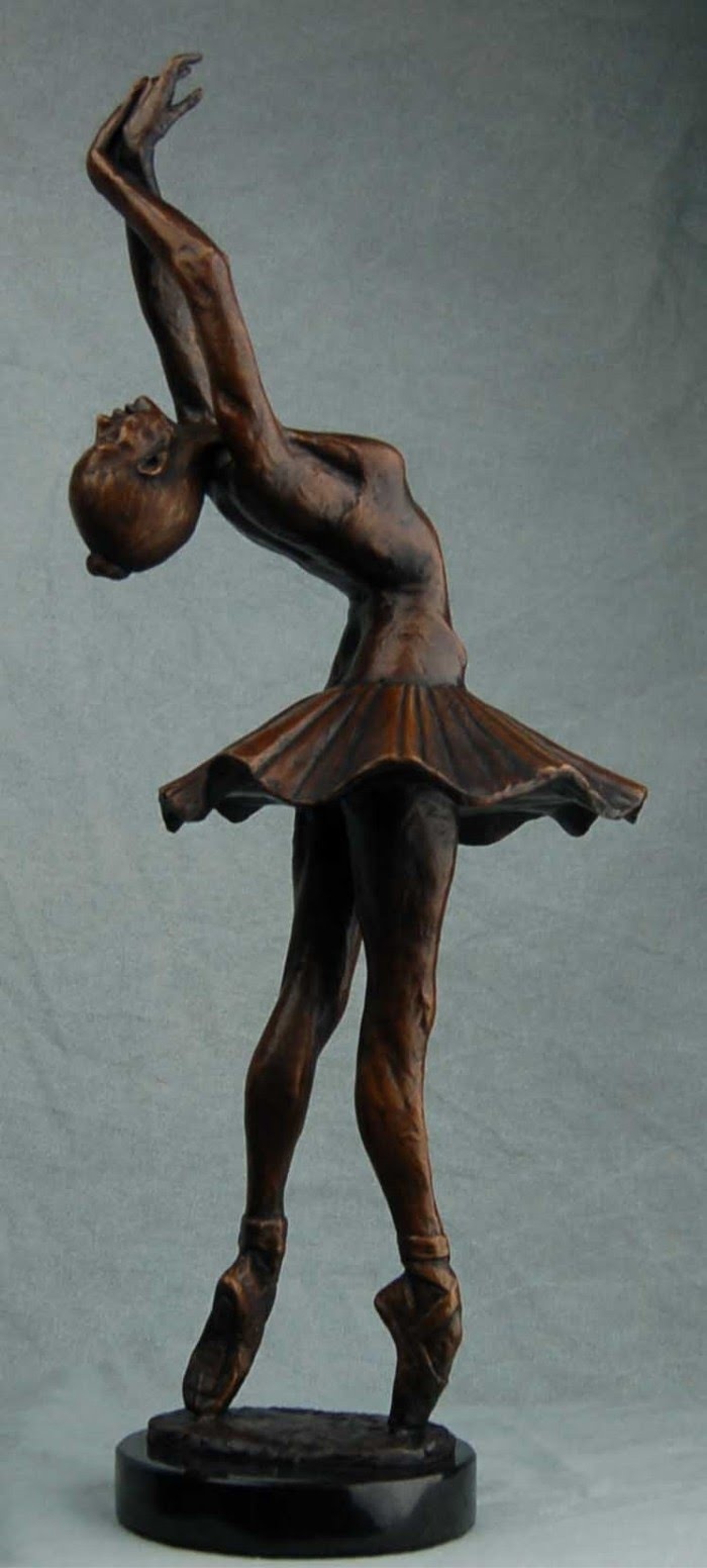 a bronze statue of a ballerina on a white background