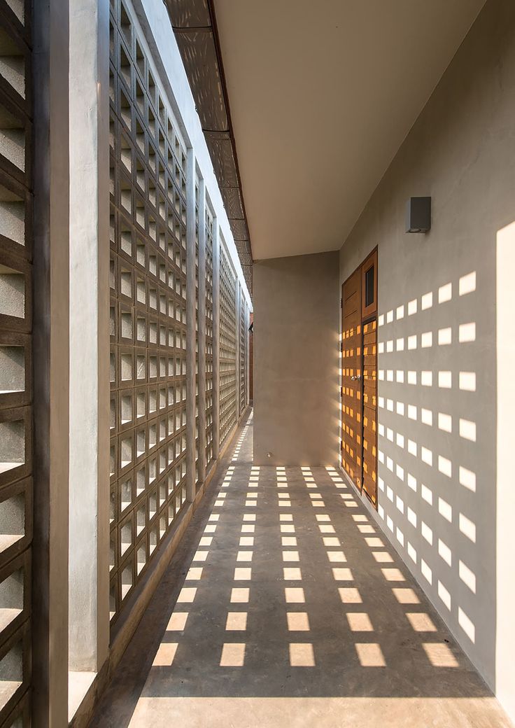 the shadows are cast on the wall and floor in front of the building's windows