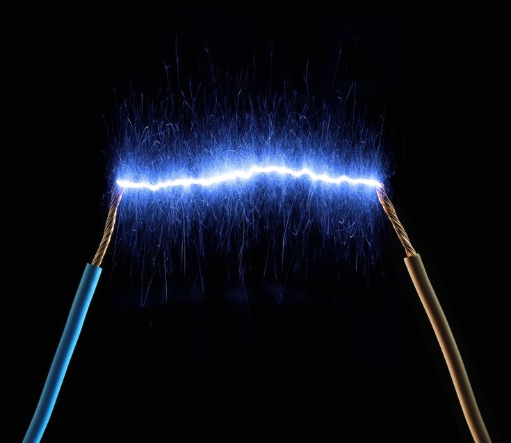 two electric wires are connected to one another with blue lightening in the dark background