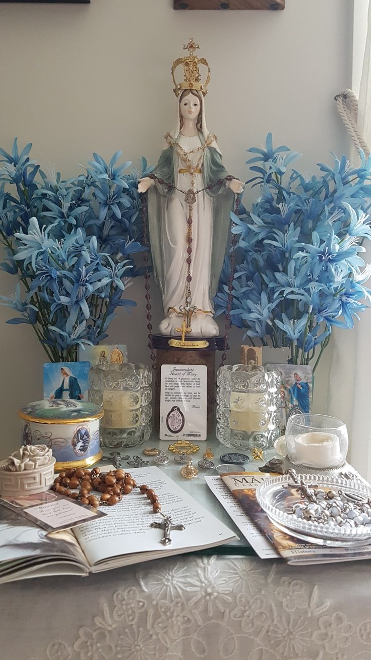 a table topped with blue flowers next to a statue and books on top of it