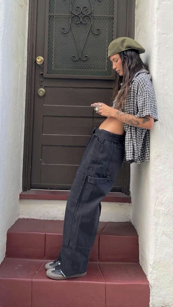 a woman standing on the steps looking at her cell phone in front of a door